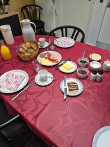 a red table with plates of food and bread on it at Marias house i Agger in Vestervig