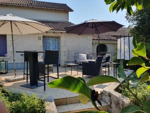 a patio with a table and chairs and umbrellas at Le Presbytère Bed & Breakfast in Saint-Romain