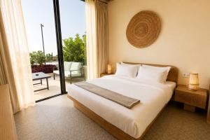 a bedroom with a large white bed and a balcony at Inanna Resort in Kifrayyā