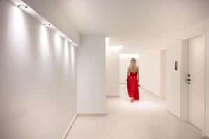 Eine Frau in einem roten Kleid geht in einem weißen Flur in der Unterkunft Toska Tower in Chrisi Ammoudia