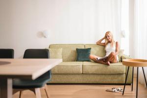 a woman sitting on a couch in a living room at Hotel Gartenresidence Zea Curtis in Merano +132 photos