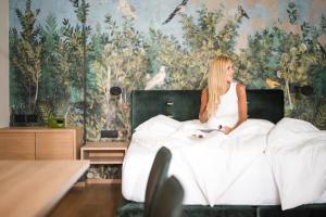 a woman sitting on a bed with a dog at Hotel Gartenresidence Zea Curtis in Merano