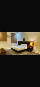 a bedroom with a large bed and a nightstand and a bed sidx sidx sidx at شقق واحة اجا in Hail