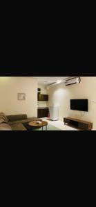 a living room with a couch and a flat screen tv at شقق واحة اجا in Hail