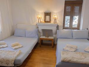 two beds in a room with a table and two lamps at Eternal blue in Volos