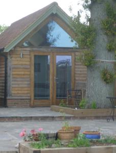 a wooden cabin with a tree at Little Oak - Small Rural Self Contained Oak Barn Unit - Sleeps 2 in Haslemere