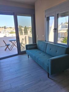 a living room with a blue couch and a balcony at katina 26 in Pitsidia