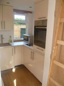 a kitchen with white cabinets and a microwave and a window at Little Oak - Small Rural Self Contained Oak Barn Unit - Sleeps 2 in Haslemere