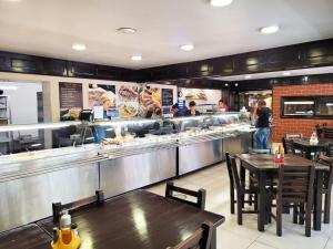 a restaurant with tables and a kitchen with people preparing food at Pensiune Iguana in Tulcea