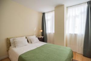 een slaapkamer met een bed met een groene deken en een raam bij Little River View Triplex in Alfama in Lissabon