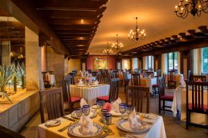 um restaurante com mesas e cadeiras brancas e lustres em Barceló Huatulco em Santa Cruz Huatulco