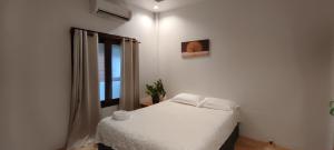 a bedroom with a white bed and a window at Neziha's Homes in Thong Sala