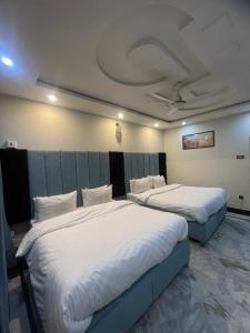 two beds in a hotel room with at Aban Guest House in Peshawar +5 photos