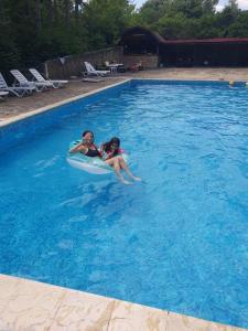two girls riding on a raft in a swimming pool at Хотел Галина Палас in Srem