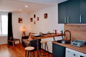 a kitchen with a table and a couch in a room at Dormir à Brioude - appartement 'esprit dune' in Brioude