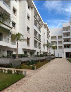 a large white building with palm trees in front of it at Couzi Haus Marina in Agadir