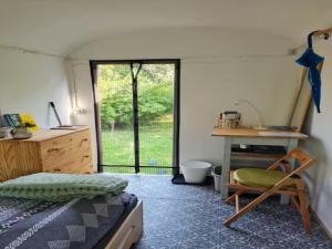 a bedroom with a bed and a desk and a window at Gemütlicher Rustikaler Bauwagen in Vippachedelhausen