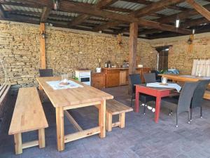 a patio with wooden tables and chairs and a stone wall at Gemütlicher Rustikaler Bauwagen in Vippachedelhausen