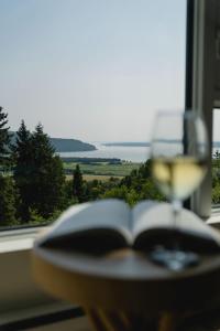 an open book and a glass of wine on a table at 211 - Bright Condo - Pool and Cozy Atmosphere in Baie-Saint-Paul +69 photos