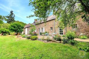 an exterior view of a brick house with a yard at La bremande in Saint-Georges-de-Reintembault