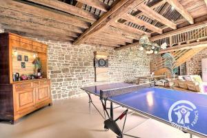 a ping pong table in a room with a brick wall at La bremande in Saint-Georges-de-Reintembault