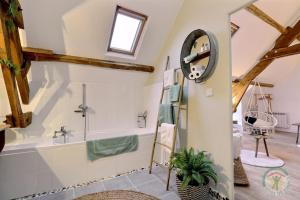 a bathroom with a tub and a clock on the wall at La bremande in Saint-Georges-de-Reintembault +40 photos