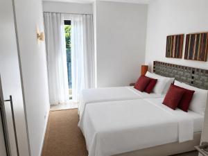 a white bedroom with two beds and a window at Azuri Appartement De Luxe & Pool in Roches Noires +47 photos
