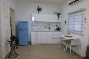 a kitchen with a blue refrigerator and a table at צימר פסטורלי בהגושרים in HaGoshrim