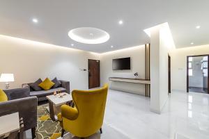 a living room with a yellow chair and a couch at فندق اورا ميلينيوم in Al Maraghah