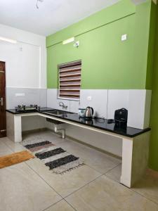 a kitchen with a black counter and green and white walls at Havens Nature Homestay in Ambalavayal