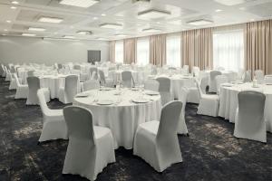 a room full of tables and chairs with white tablecloths at Courtyard by Marriott Pilsen in Pilsen