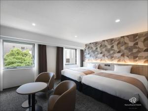 a hotel room with two beds and a window at Daiwa Roynet Hotel Oita in Oita +86 photos