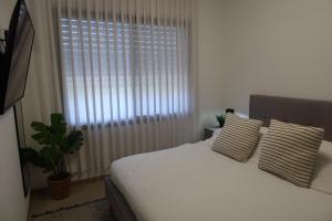 a bedroom with a white bed and a window at צימר פסטורלי בהגושרים in HaGoshrim