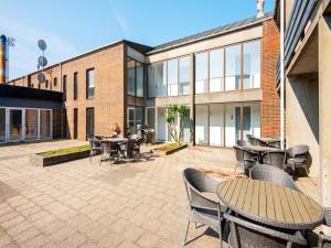 a patio with tables and chairs in front of a building at Vedersø Holiday Center in Ulfborg