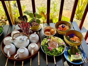a table with plates of food and bowls of food at บ้านไม้ชายแดนกาแฟสดแอนด์โฮมสเตย์ in Ban Ba Nam Ron