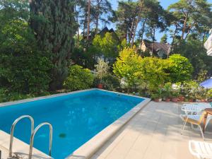 a swimming pool in a yard with chairs and trees at Aquasol Apartman in Siófok