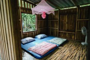 a room with two beds and a window at บ้านไม้ชายแดนกาแฟสดแอนด์โฮมสเตย์ in Ban Ba Nam Ron