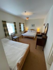a bedroom with two beds and a table and a bed at Ardtarmon House in Sligo