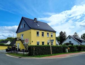 a yellow house with a black roof on a street at Ferienwohnung Brunnenaue in Sagard