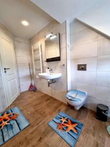 a bathroom with a sink and a toilet and starfish mats at Ferienwohnung Brunnenaue in Sagard +21 photos