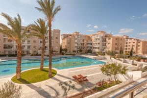 an apartment with a swimming pool and palm trees at Elysia Park in Paphos