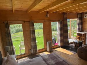 a room with large windows in a wooden house at Star Gazer Cabin in Inversnaid
