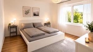 a white bedroom with a large bed and a window at Köln Pulheim Wellness Oase in Pulheim