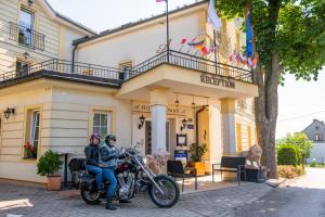 Zwei Personen sitzen auf einem Motorrad vor einem Gebäude in der Unterkunft Hotel Tommy Wellness & Spa in Náchod + 80 Fotos