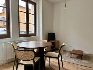 a room with a table and chairs and a tv at La Halte Beaujolaise in Belleville-en-Beaujolais
