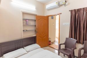 a bedroom with a bed and a chair and a door at KUKAL CASTLE in Tiruppūr