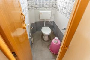 a small bathroom with a toilet and a pink bucket at KUKAL CASTLE in Tiruppūr