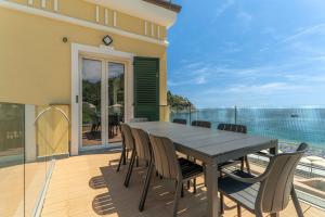 a dining table and chairs on a balcony with the ocean at SeaFrontBonassola in Bonassola