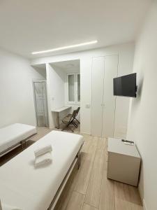 a white room with two beds and a flat screen tv at Colombo 365 in Civitanova Marche