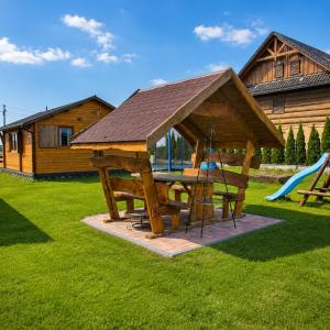 a wooden picnic table with a pitched roof with a playground at Witówka Bieliny in Bieliny +19 photos
